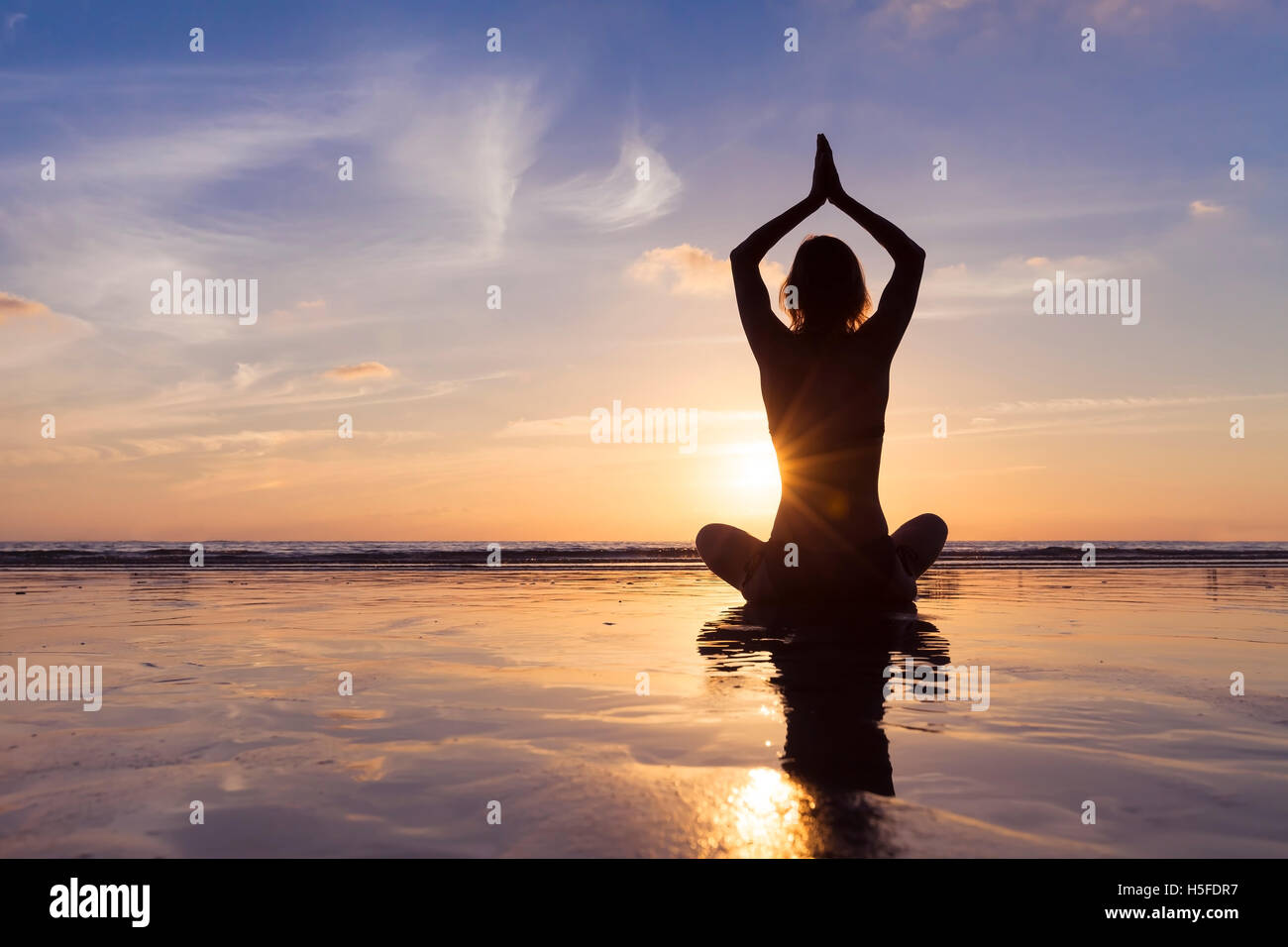 Colocar joven mujer que utiliza la técnica de yoga para la meditación y el bienestar en la playa al amanecer. Foto de stock