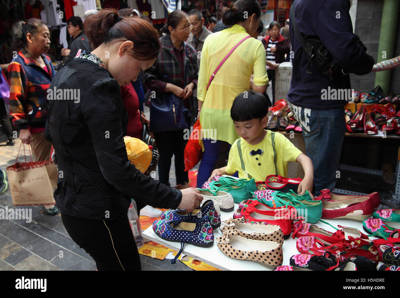 Mujer China está en busca de zapatos se pueden comprar y el hijo del de la tienda está tratando de ayudarla. Qibao Old Street Fotografía de - Alamy