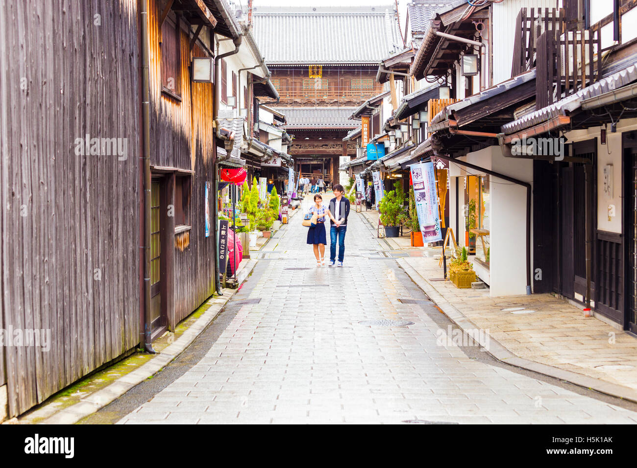 La gente pasea por las calles tradicionales de Nagahama vacío entre tiendas turísticas en frente de Daitsu-ji templo budista, Japón. Horizo Foto de stock