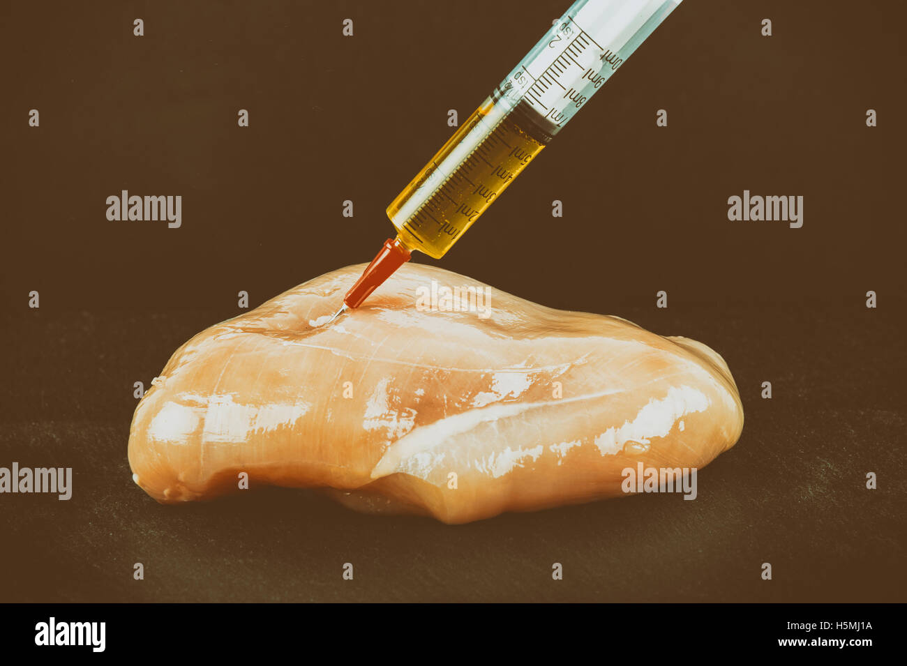 Jeringa con líquido inyectado a un trozo de carne. Ilustración conceptual de hormonas y antibióticos en la producción de alimentos. Foto de stock