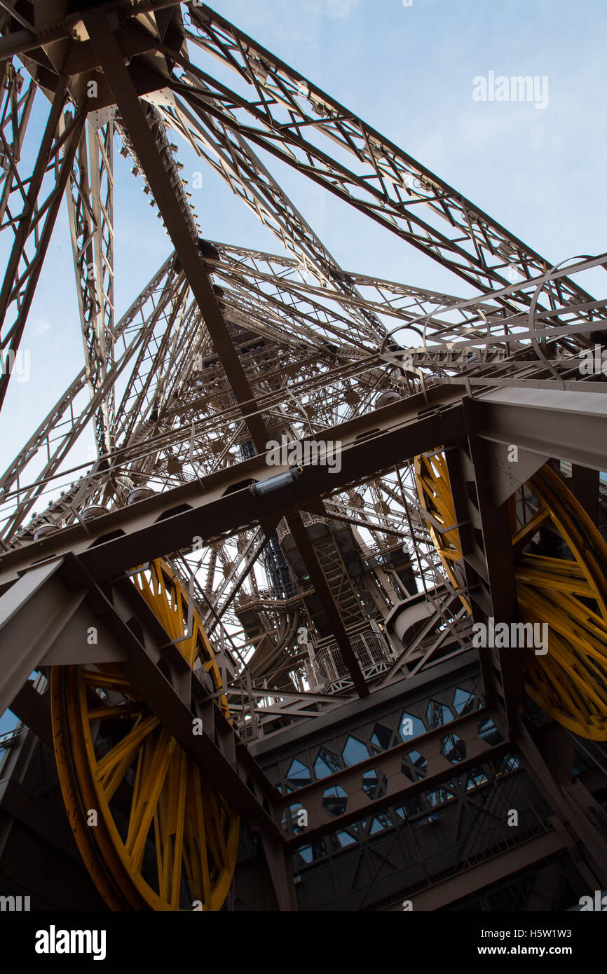 Una vista de la Torre Eiffel desde abajo con las ruedas grandes que controla los ascensores. Foto de stock