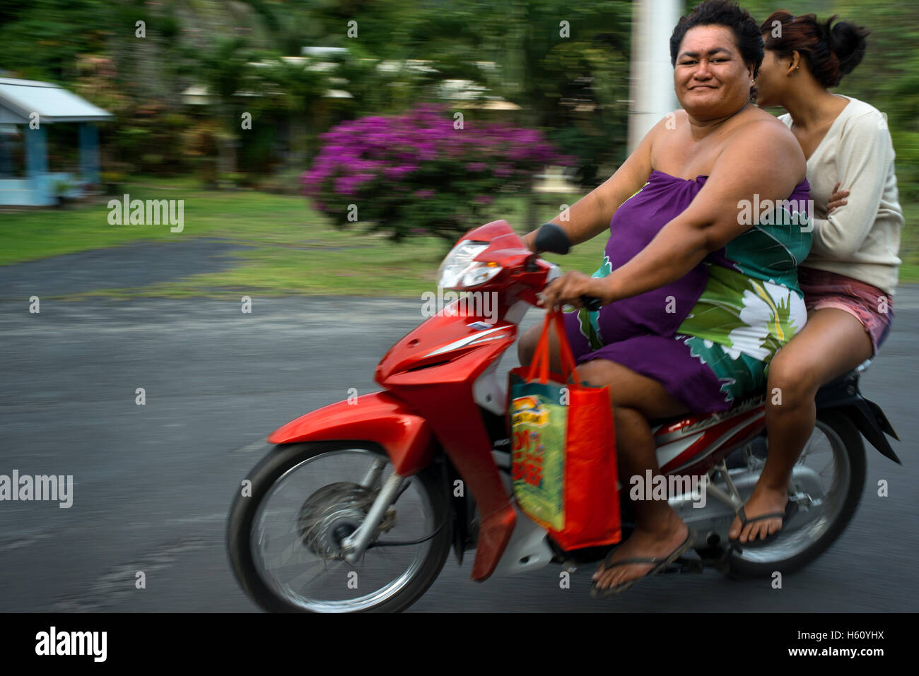 La Isla de Rarotonga. Islas Cook. La Polinesia. Océano Pacífico Sur. Dos personas obesas conducir una motocicleta en una carretera en la isla de Ra Foto de stock