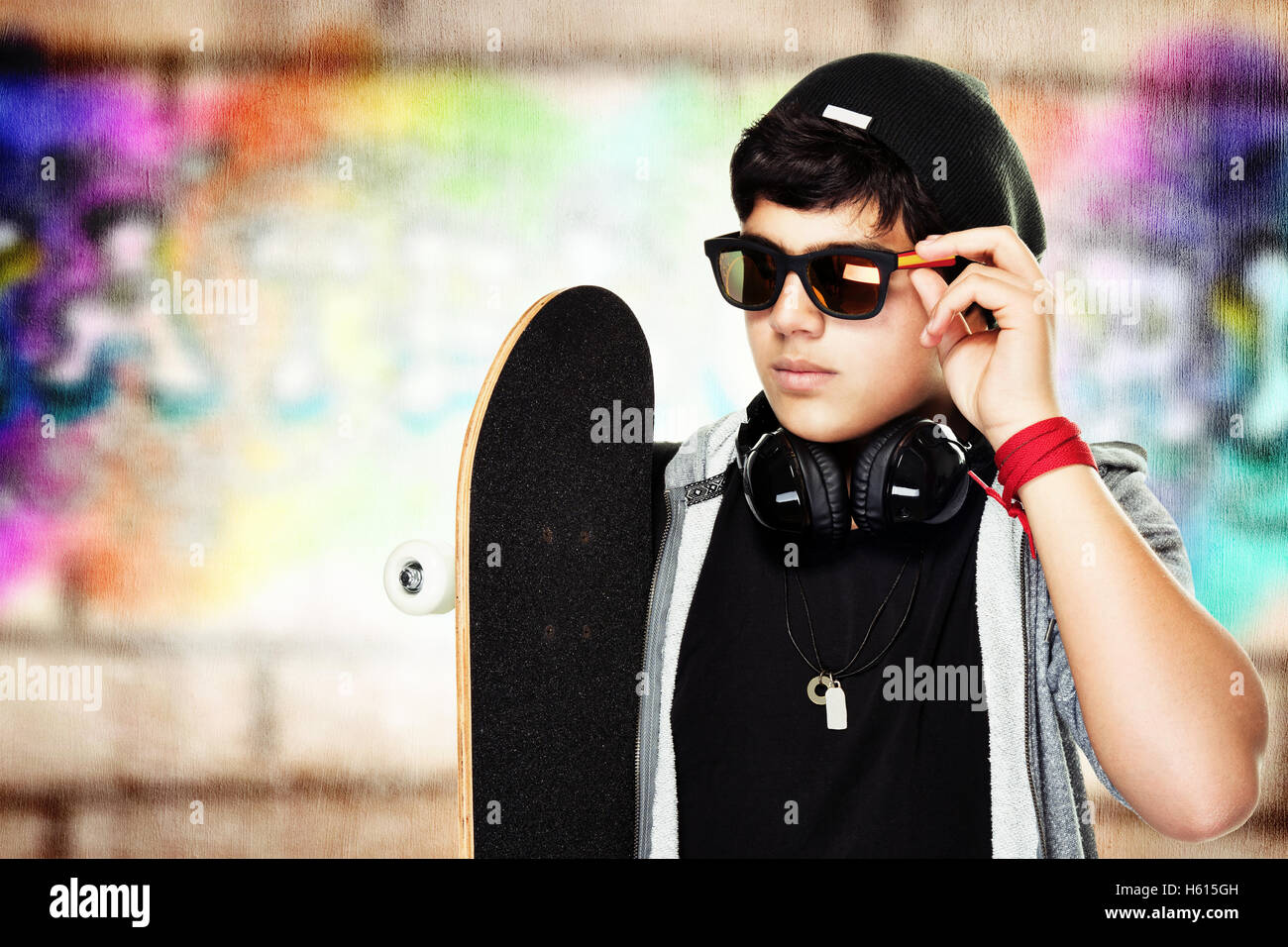 Retrato de un patinador guapo con gafas de sol y sombrero elegante al aire libre, activa teen elegante Foto de stock