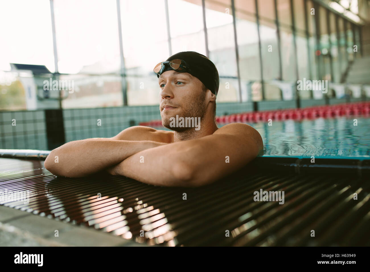 Foto de joven en el borde de la piscina. Pro nadador masculino descansando después de nadar. Foto de stock