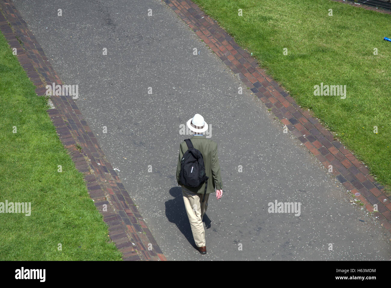 Bien vestida gentleman inglés en un sombrero panamá estilo cricket caminando por la carretera Foto de stock