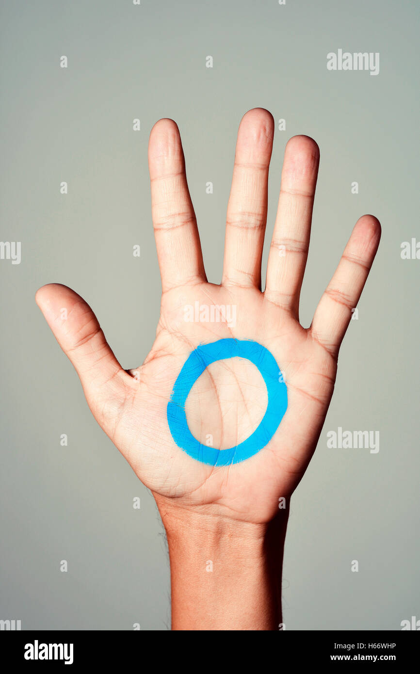 Un círculo azul, símbolo de la diabetes, pintado en la palma de la mano de un hombre joven, en apoyo de los diabéticos Foto de stock