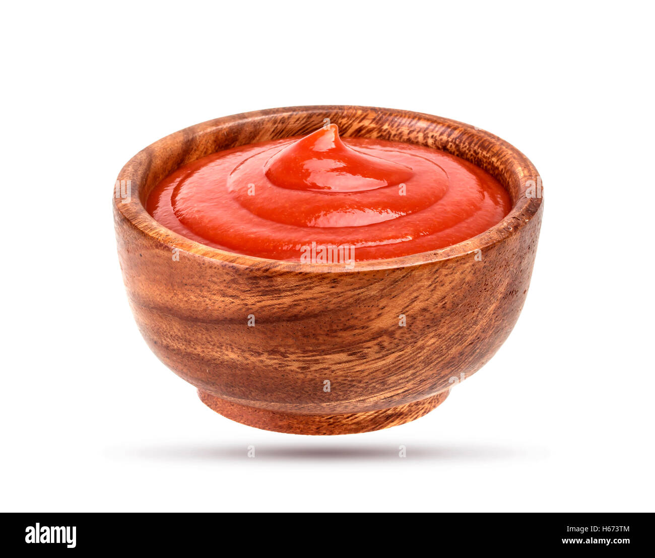 Ketchup en el tazón de madera aislado en blanco Foto de stock