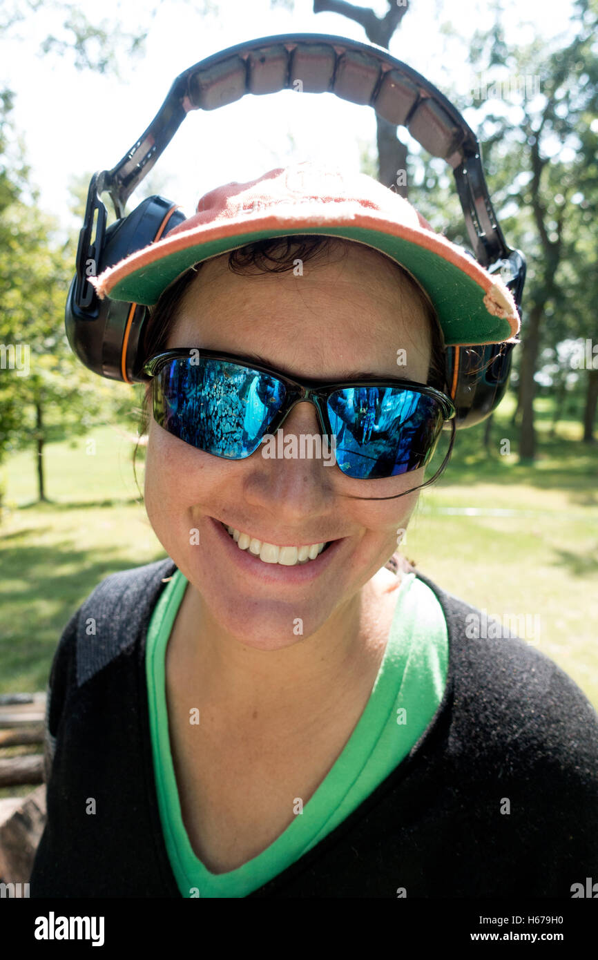 Mujer feliz después de terminar la temporada de siega una gran extensión de césped vistiendo oreja y protección ocular. Clitherall MN Minnesota EE.UU. Foto de stock