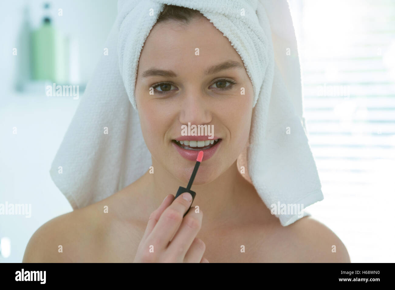 Mujer aplicar lip gloss en sus labios en el baño. Foto de stock