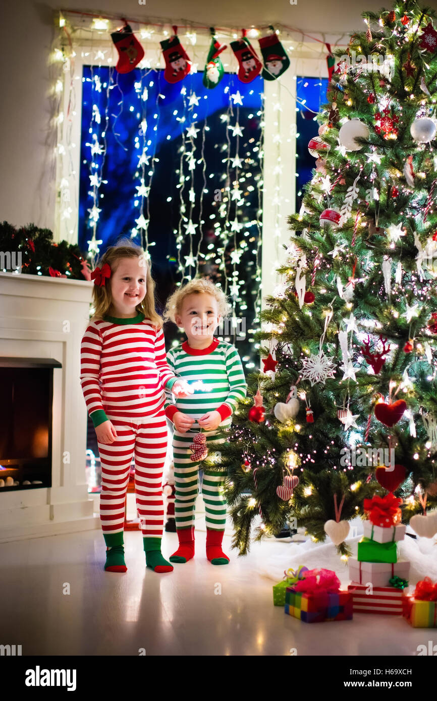 Poco feliz coincidencia de chicos en pijama de rayas rojas y verdes decorar  árbol de Navidad en la hermosa sala de estar con chimenea Fotografía de  stock - Alamy