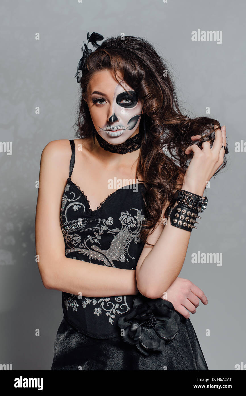 Mujer joven en negro con calavera media cara maquillaje Fotografía de stock  - Alamy