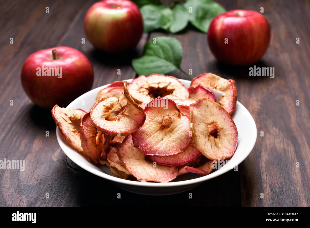 Snack de frutas deshidratadas chips de manzana en el recipiente sobre la  mesa de madera Fotografía de stock - Alamy