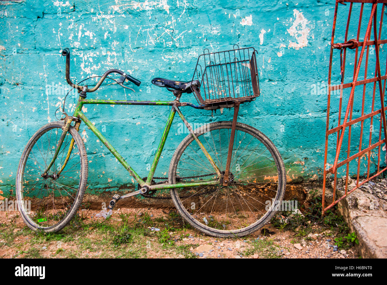 Viejo verde bicicleta por teal pared y puerta roja Foto de stock