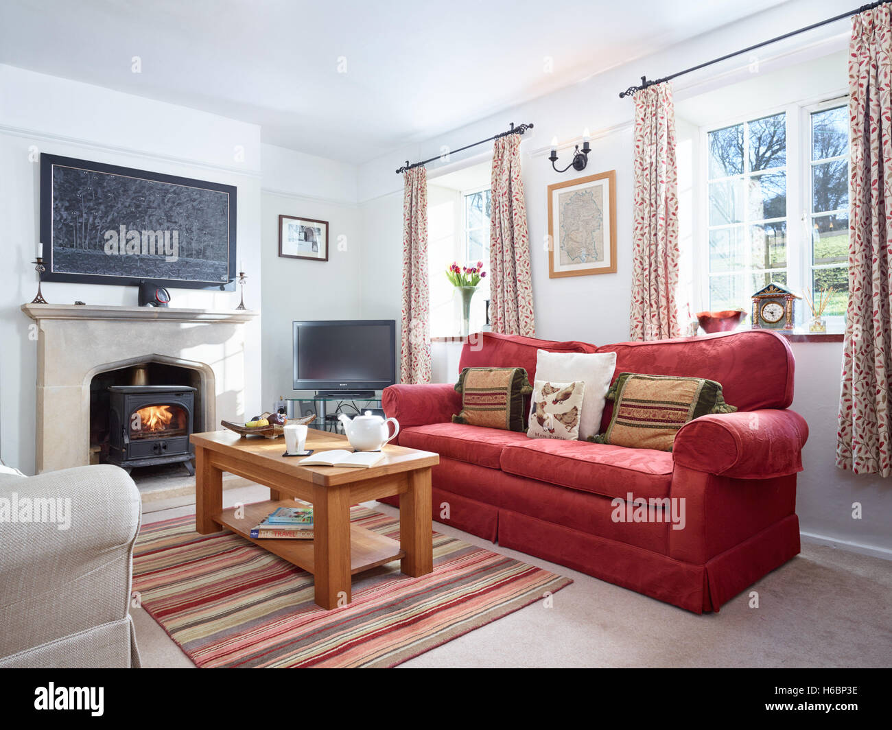 Un acogedor salón con chimenea y un quemador de madera en una confortable casa de campo. Foto de stock