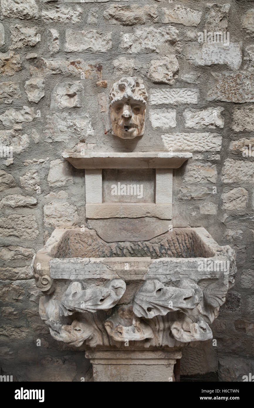 Cara de piedra con fuente de agua de la cuenca, el Palacio de Diocletian, Split, Croacia Foto de stock