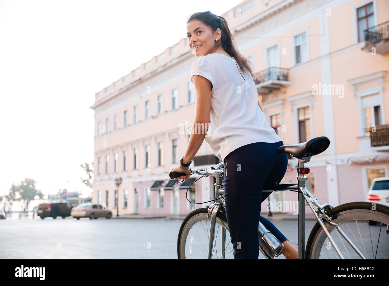 Retrato de una mujer encantadora montando en bicicleta en las calles de la ciudad Foto de stock