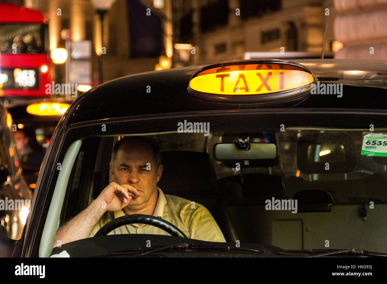 Un conductor de taxi nocturno de aspecto cansado en el West End de Londres Foto de stock