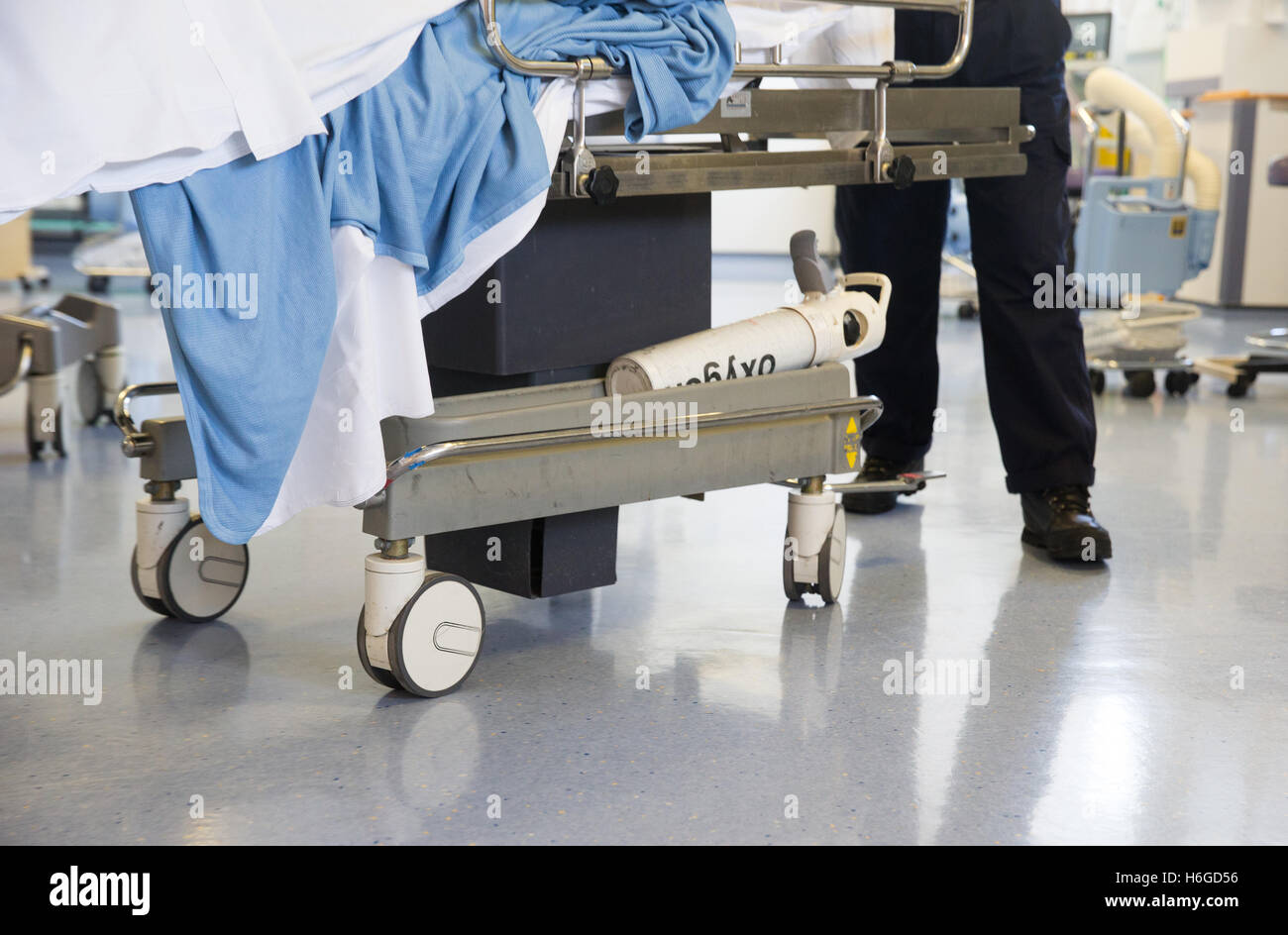 Un trabajador del hospital a un paciente en una de las ruedas a través de un trolley ward después de una operación de NHS Foto de stock