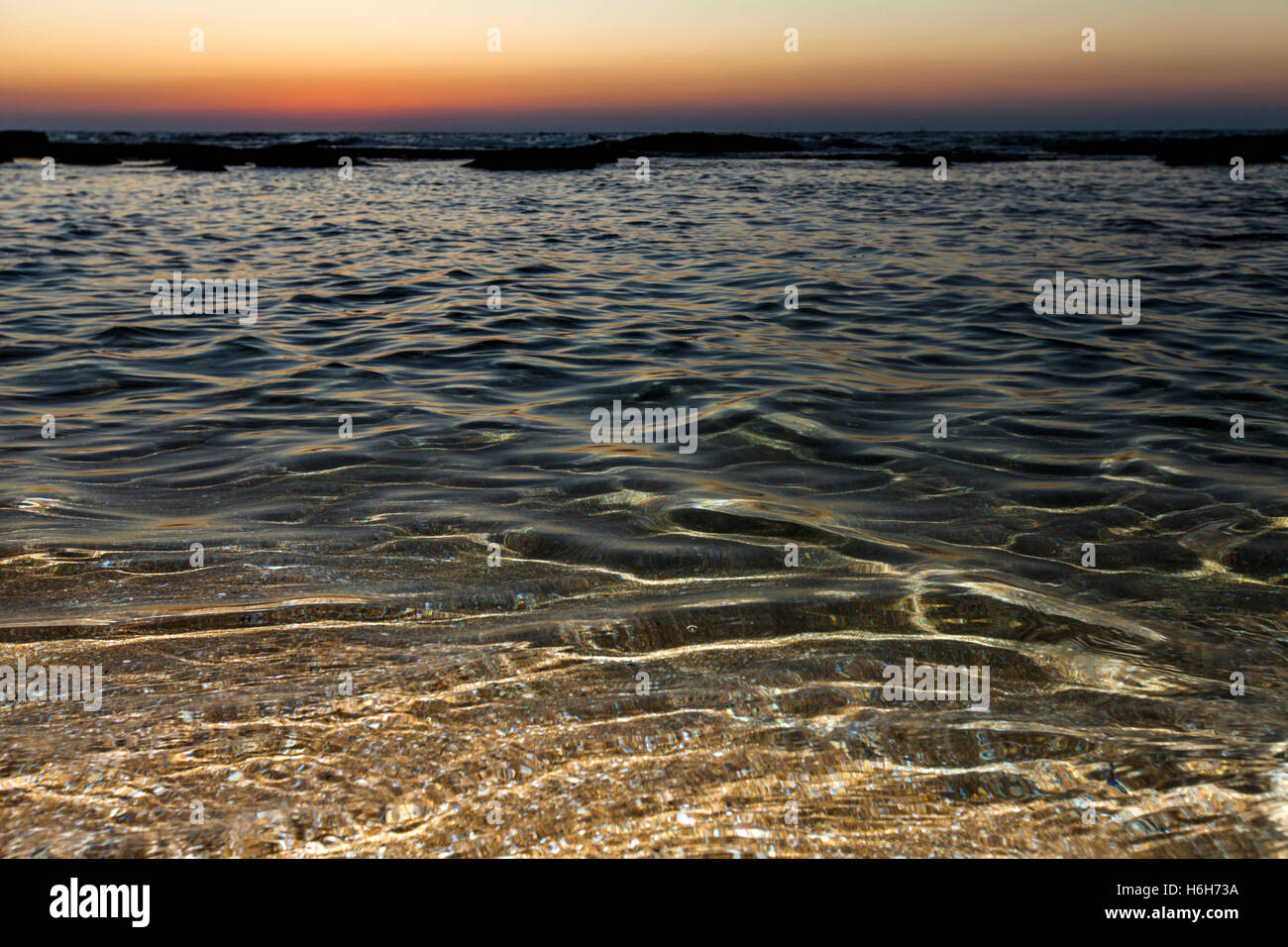 Agua de mar superficial iluminada en conjunción por flash y por último de la luz del día al anochecer. Foto de stock