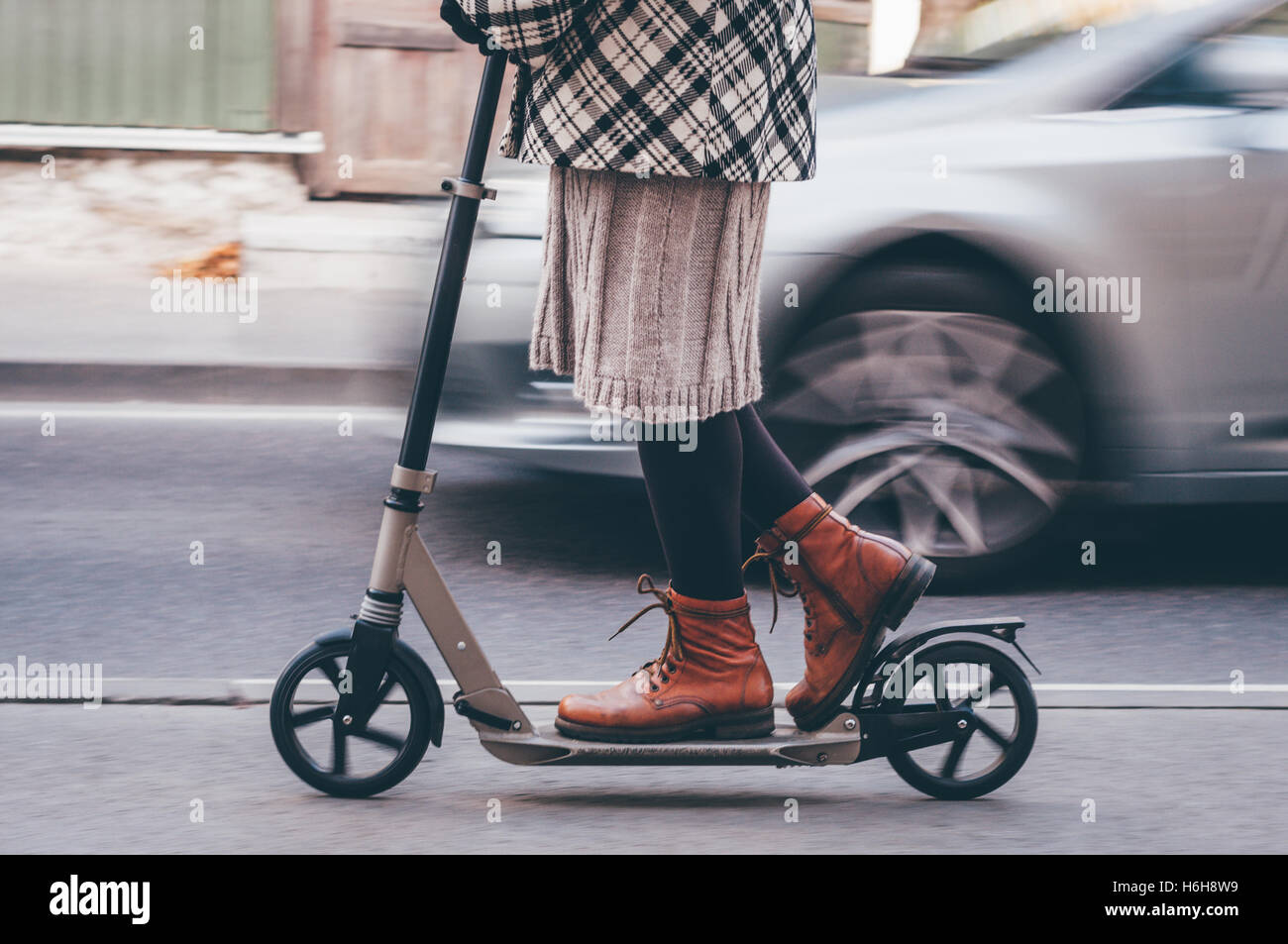 Chica en ropa casual en kick scooter en las calles de la ciudad. Efecto vintage retro Instagram tonos Foto de stock