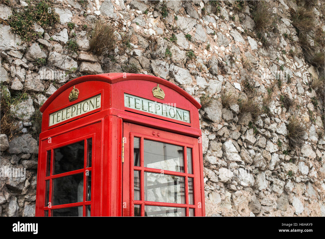 Cabina de teléfono rojo y muro de piedra Foto de stock