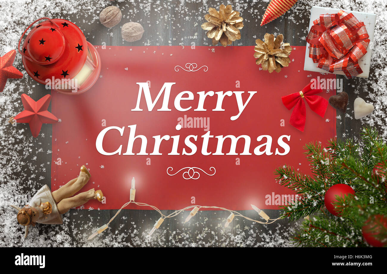 Feliz Navidad tarjeta de felicitación con árbol de navidad, regalos, decoraciones, linterna, mantel y copos de nieve sobre la plancha de madera. Foto de stock