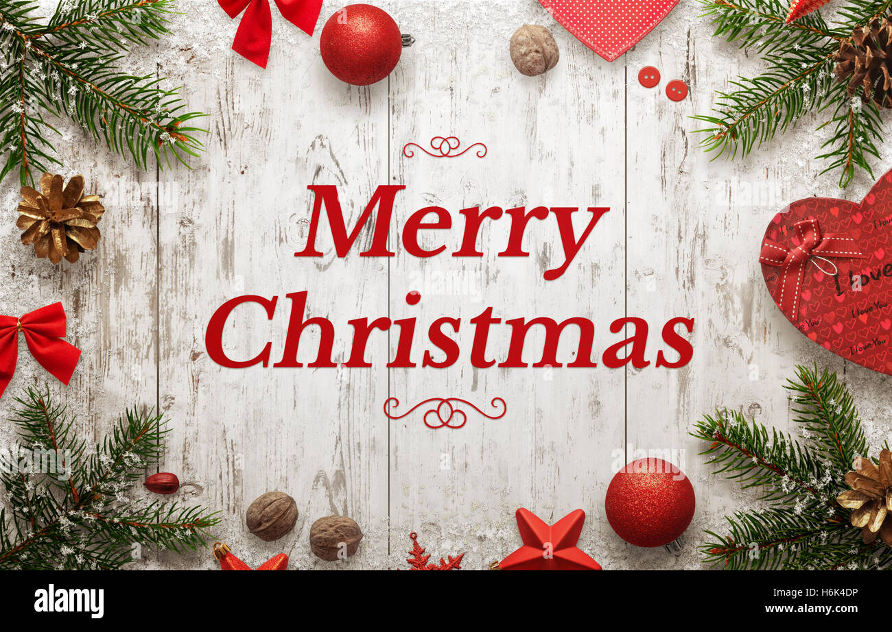 Feliz Navidad tarjeta de felicitación con el texto y las decoraciones de navidad en placa de madera blanca. Foto de stock