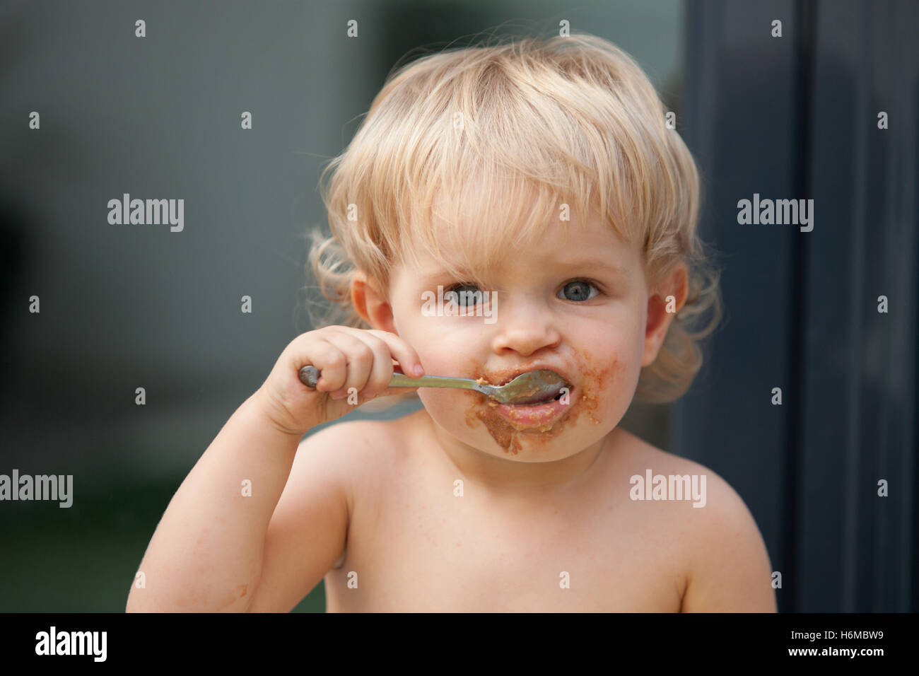Gracioso bebe rubia comiendo chocolate con una cuchara Foto de stock
