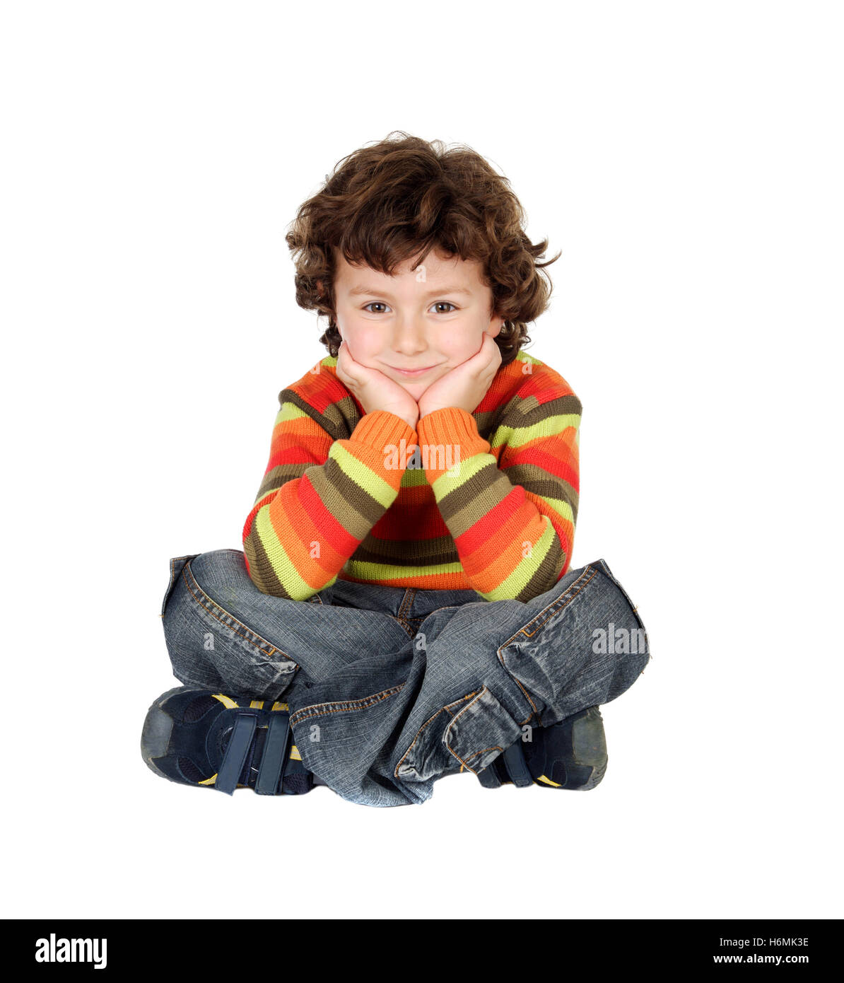 Agradable muchacho con siete años sentado en el piso blanco pensando Foto de stock
