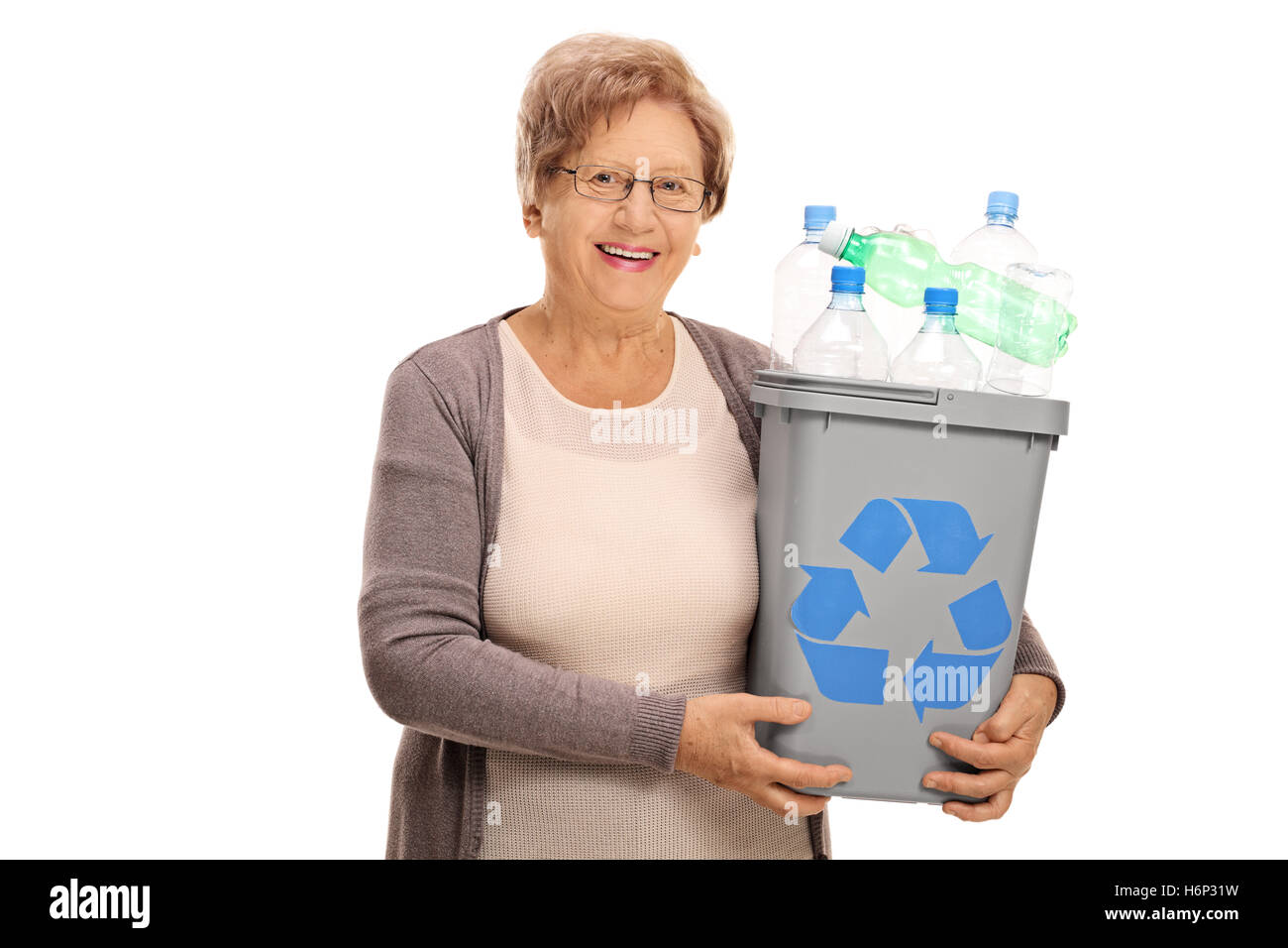 Feliz mujer madura sosteniendo una bandeja llena de reciclado de botellas de plástico aislado sobre fondo blanco. Foto de stock