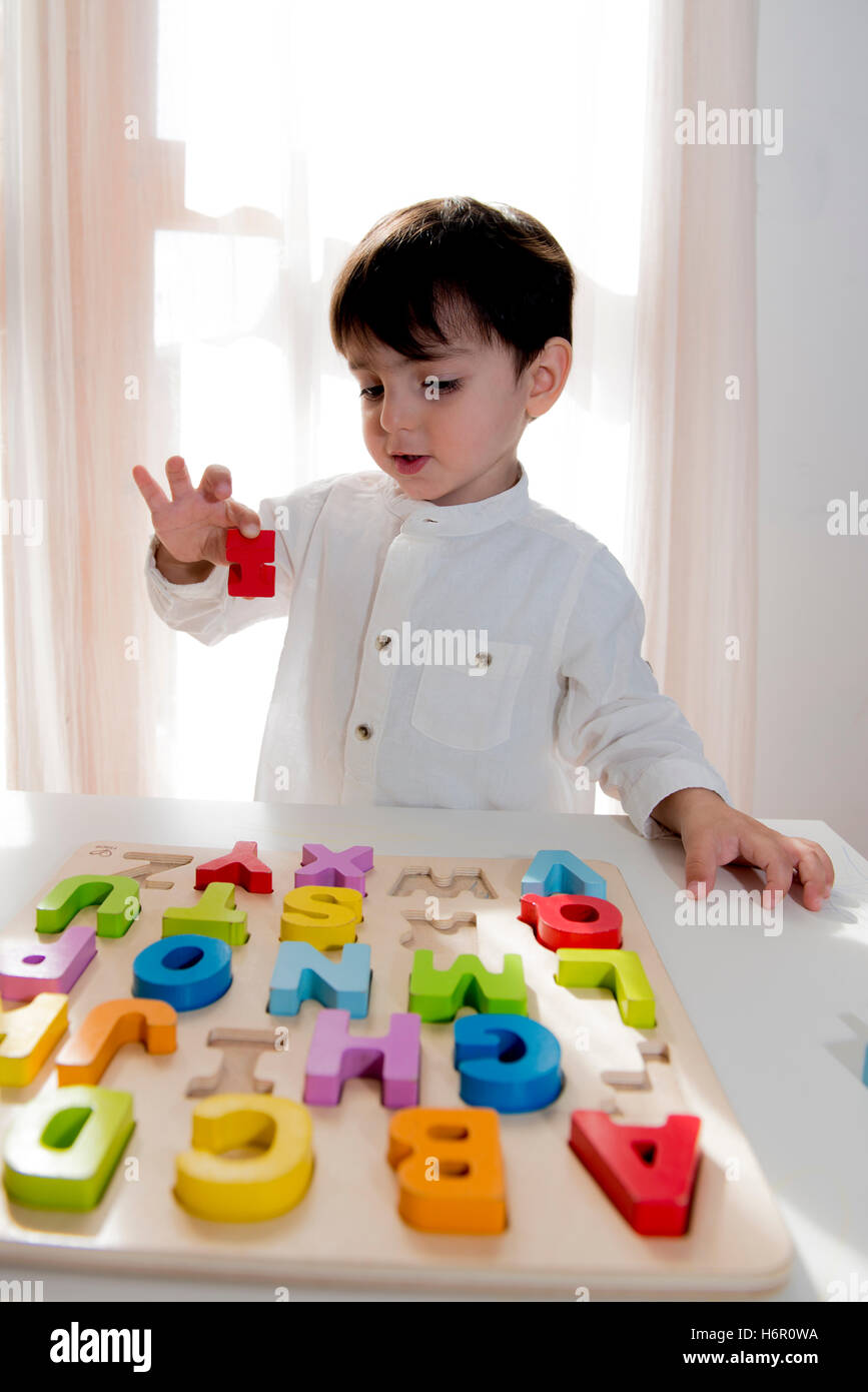 Un niño juega con letras de madera para desarrollar la inteligencia de juego preescolar Foto de stock