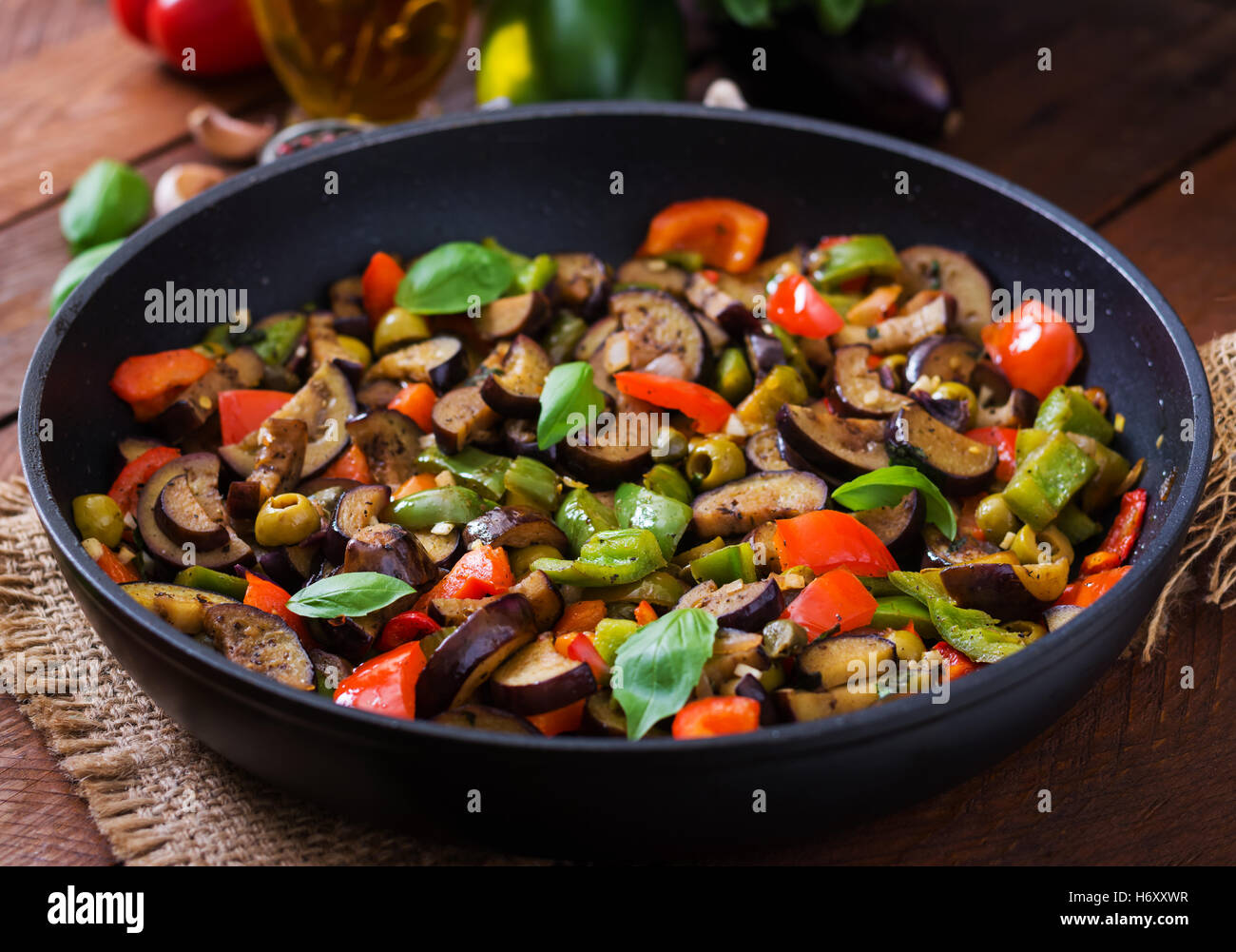 Guisado picante caliente la berenjena, el pimiento, las aceitunas y las alcaparras con hojas de albahaca. Foto de stock