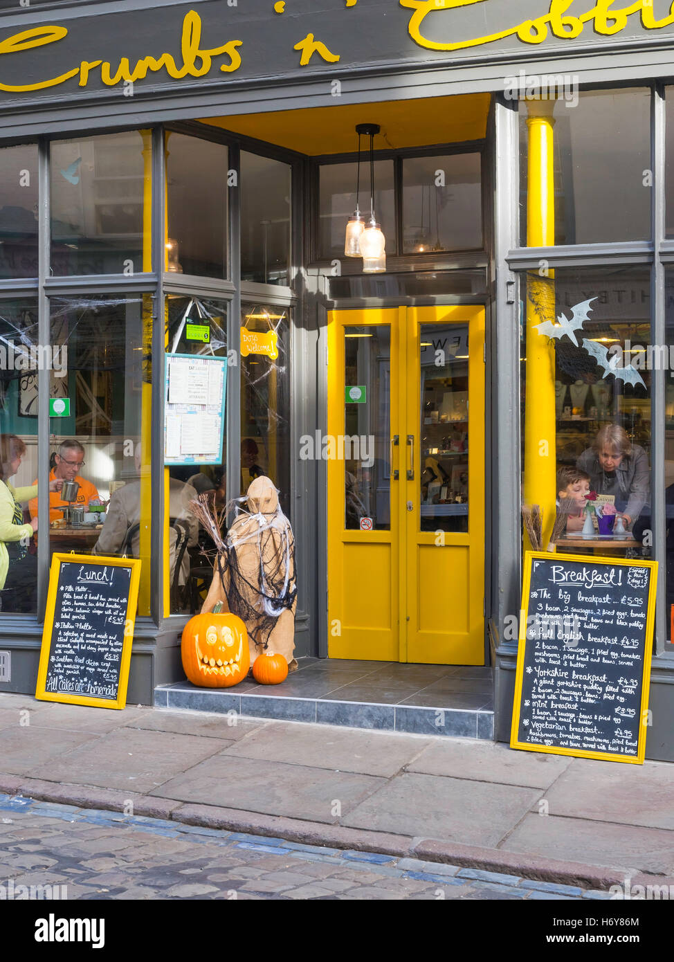 Migas 'n' adoquines Café Church Street Whitby Yorkshire ofreciendo la tradicional comida, decorada con una figura de Halloween y calabazas Foto de stock