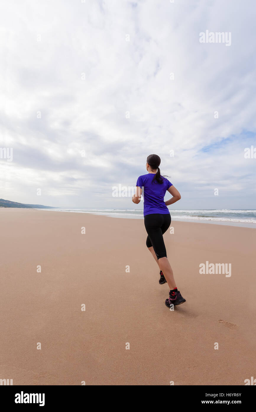 Ejecutando la atleta femenina en la playa en un día de otoño. Foto de stock