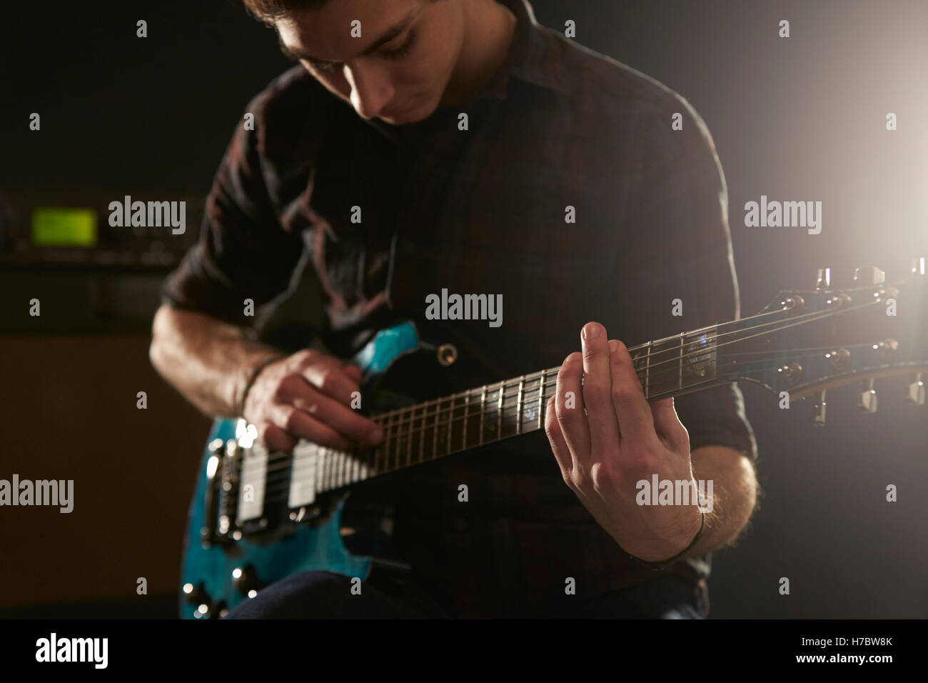 Cerca del hombre mediante la técnica de tocar en guitarra eléctrica Foto de stock