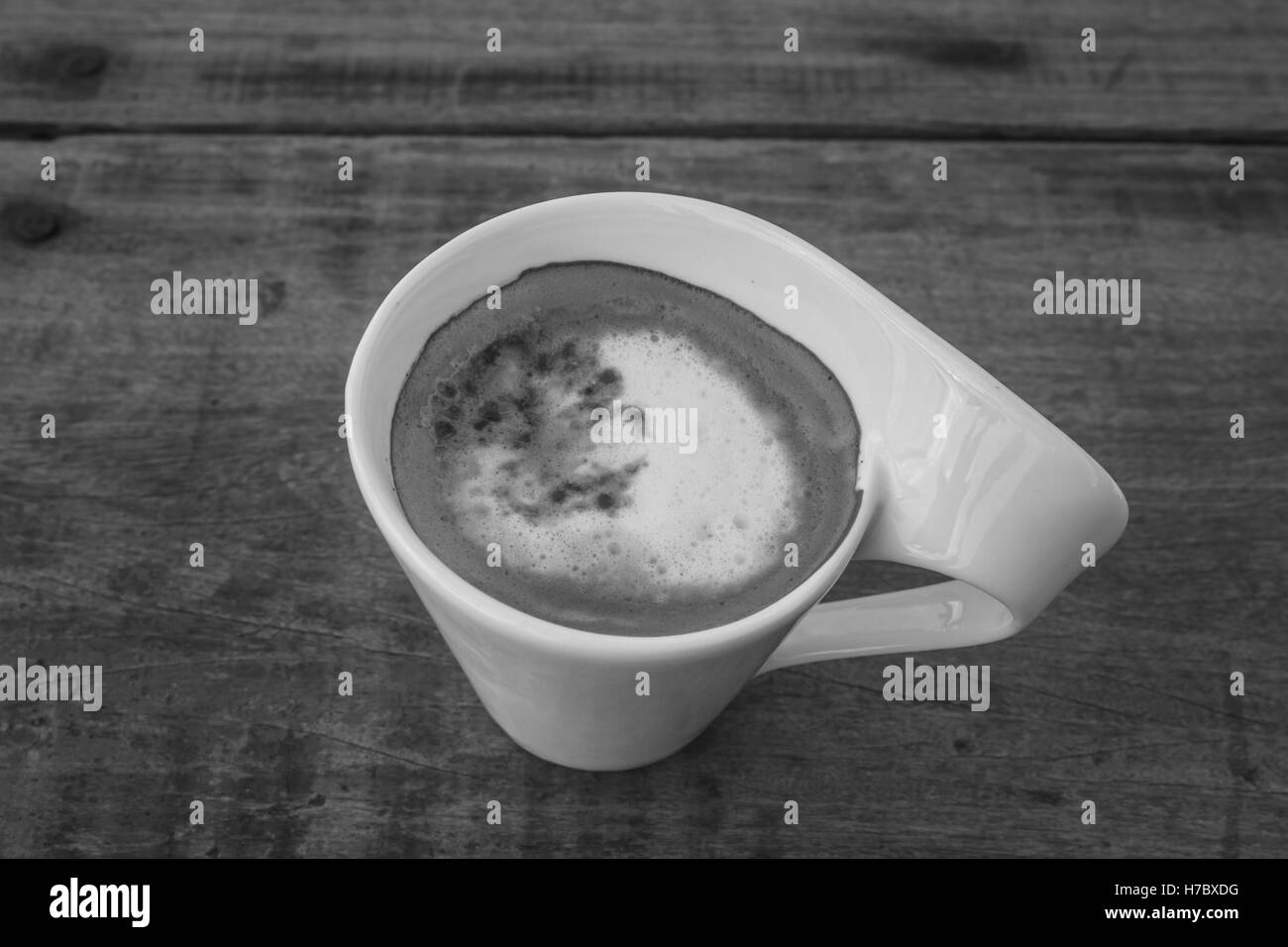 Taza de café cappuccino sobre mesa de madera y tonos de blanco y negro Foto de stock