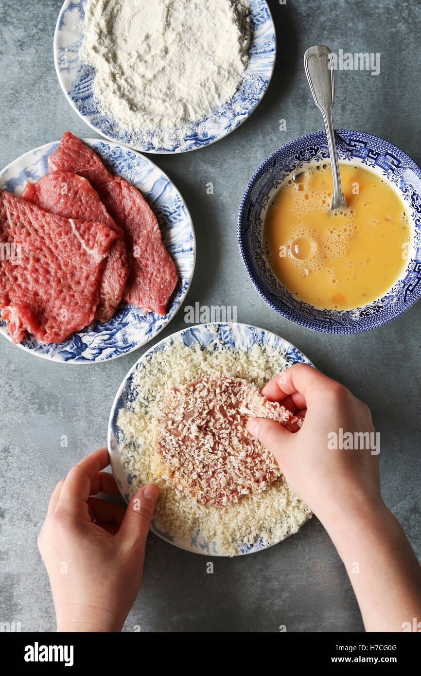 Revestimiento de manos de carne en pan rallado.Preparar schnitzel Foto de stock