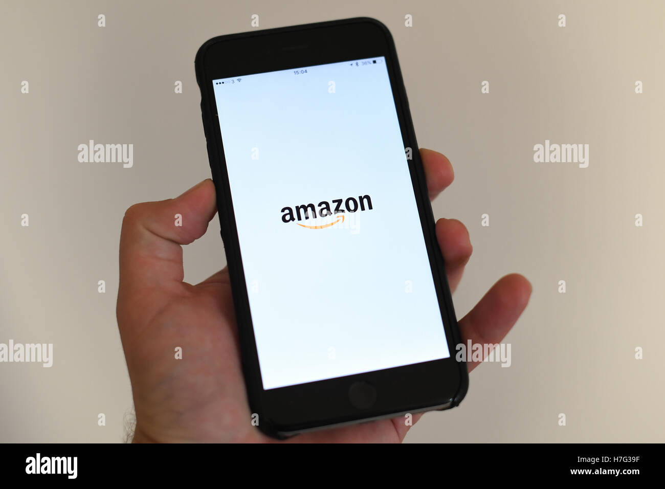Mano sosteniendo un Apple Iphone 7 Plus con el Amazon App de carga en la pantalla. Foto de stock