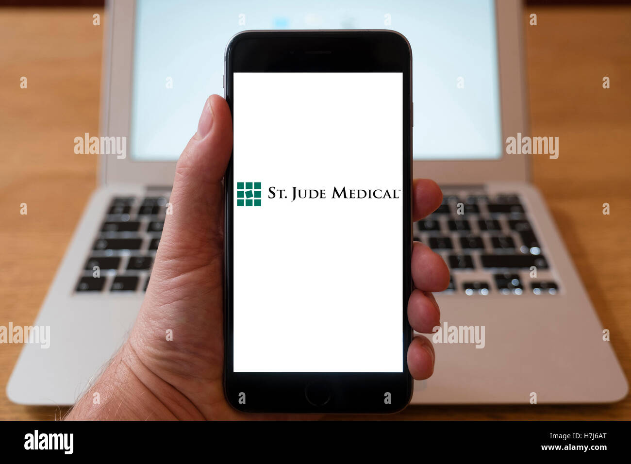 Utilizando el iPhone teléfono inteligente para mostrar el logotipo de St Jude Medical, , una compañía global de dispositivos médicos americanos Foto de stock