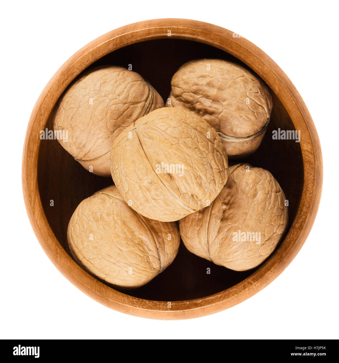Nueces enteras con cáscara en un recipiente de madera sobre fondo blanco. Los frutos secos de cáscara marrón común de nueces de nogal, Juglans regia. Foto de stock