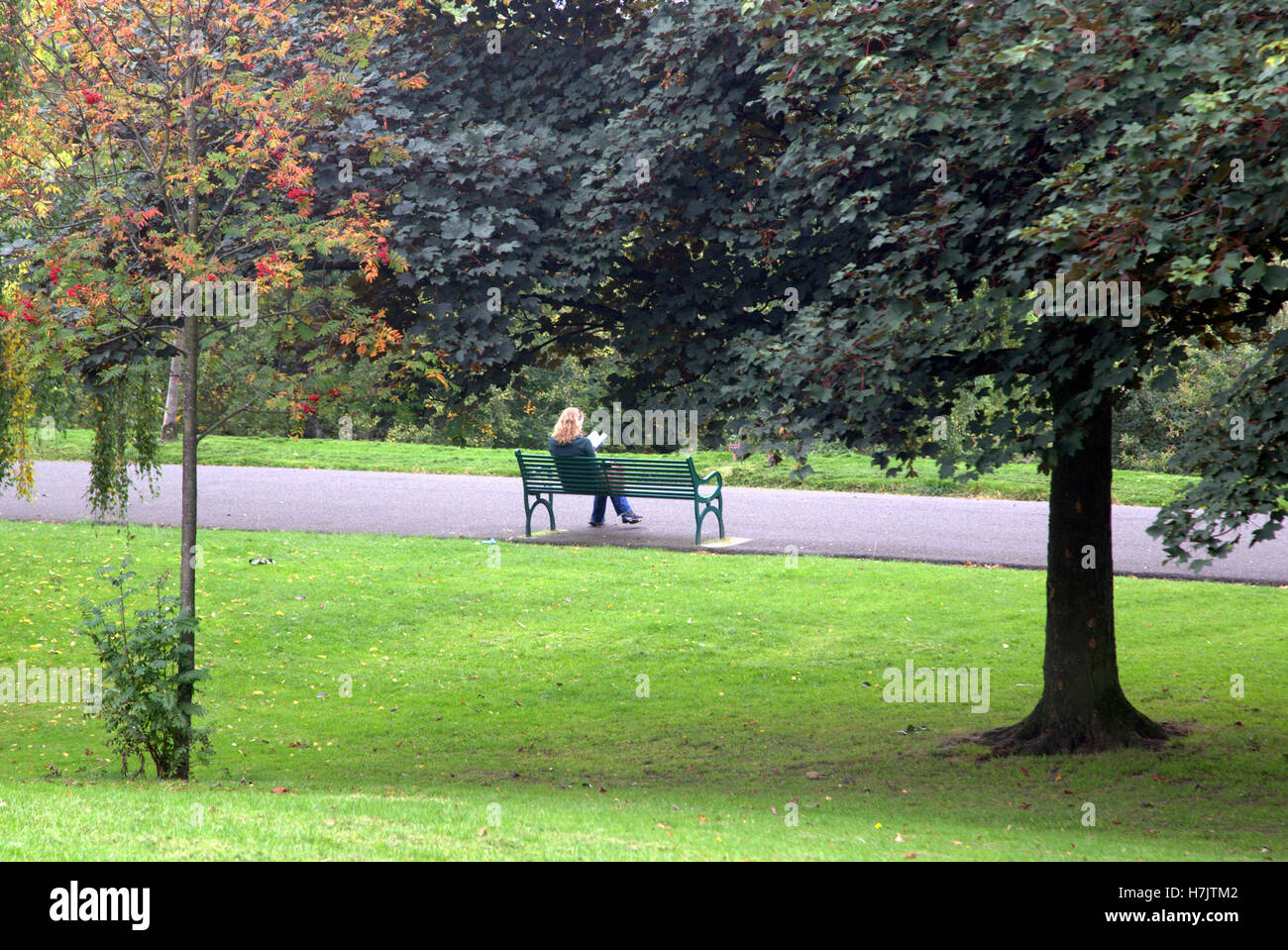 Pelo rojo chica atlética en un banco del parque Kelvingrove, Glasgow en Escocia Foto de stock