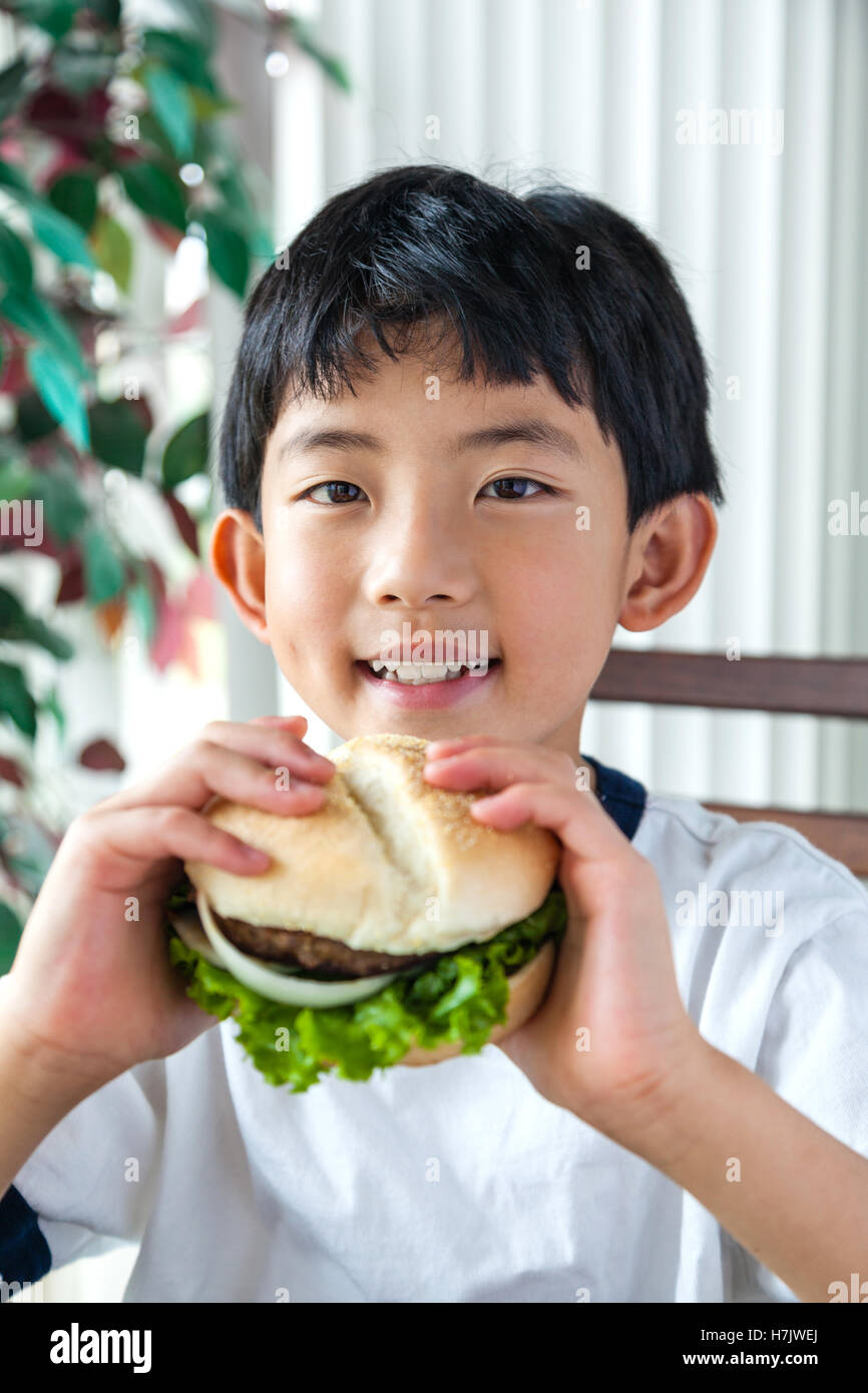 Chico asiático tener una hamburguesa para el almuerzo. Foto de stock