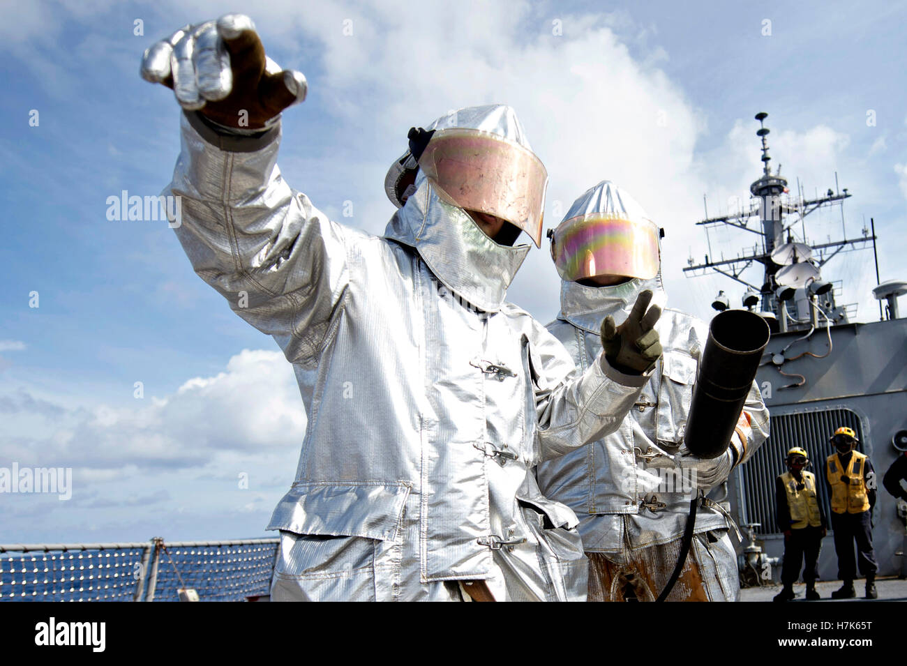 Los marineros estadounidenses llevan trajes de fuego de plata durante un accidente y rescate de perforación de formación a bordo de la cubierta de vuelo del USN Arleigh Burke clase de misiles guiados destructor USS Stethem Octubre 17, 2014 en la región del Pacífico Indo-Asia. Foto de stock