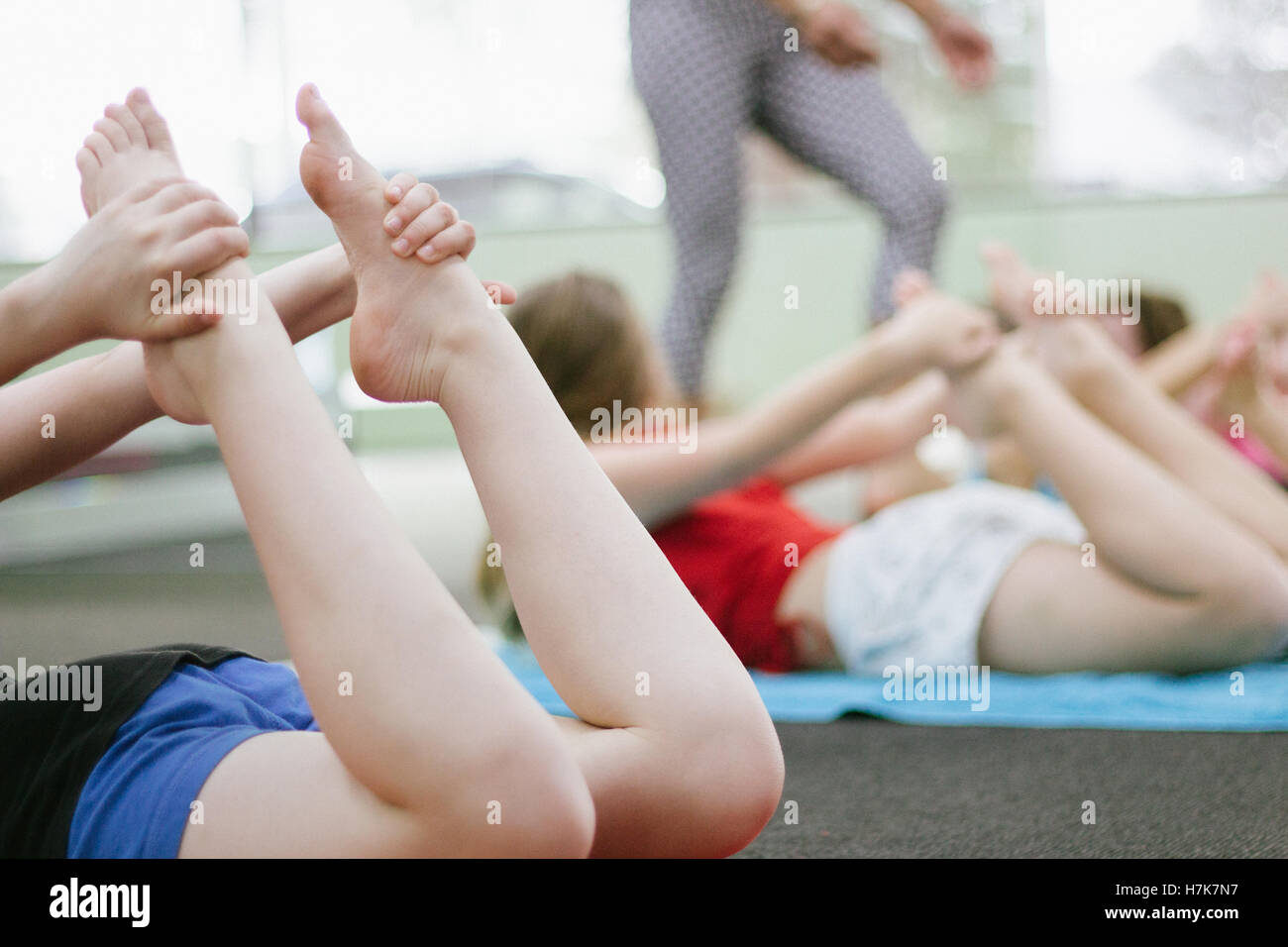 Esta imagen muestra algunos Bow pose en una clase de yoga para niños. Foto de stock