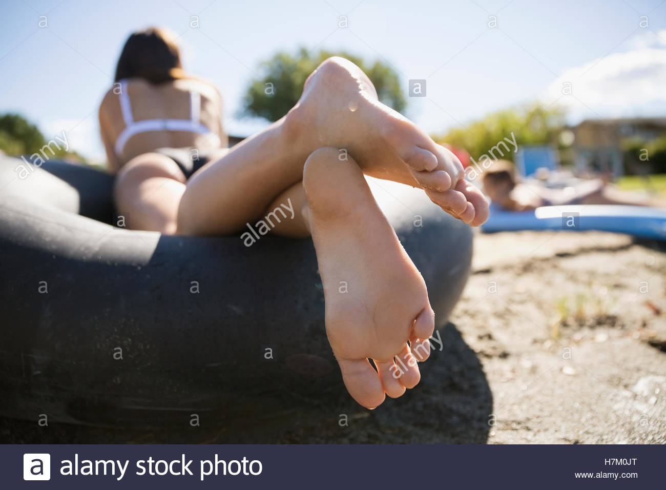 Barefoot adolescente sentando en el tubo interior en la soleada playa de verano Foto de stock