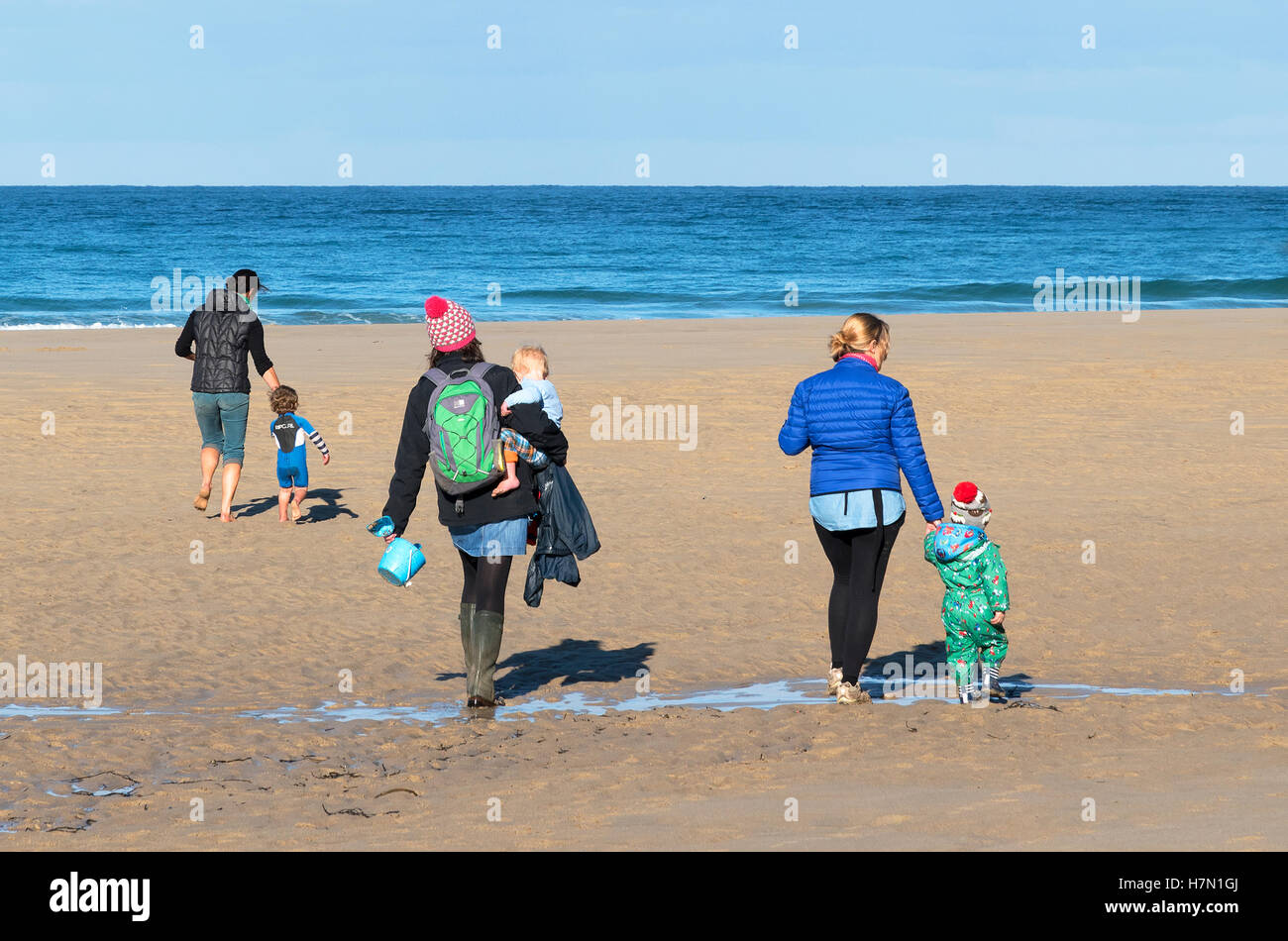 Tres jóvenes madres en una playa de Cornualles, en el Reino Unido, con sus hijos. Foto de stock