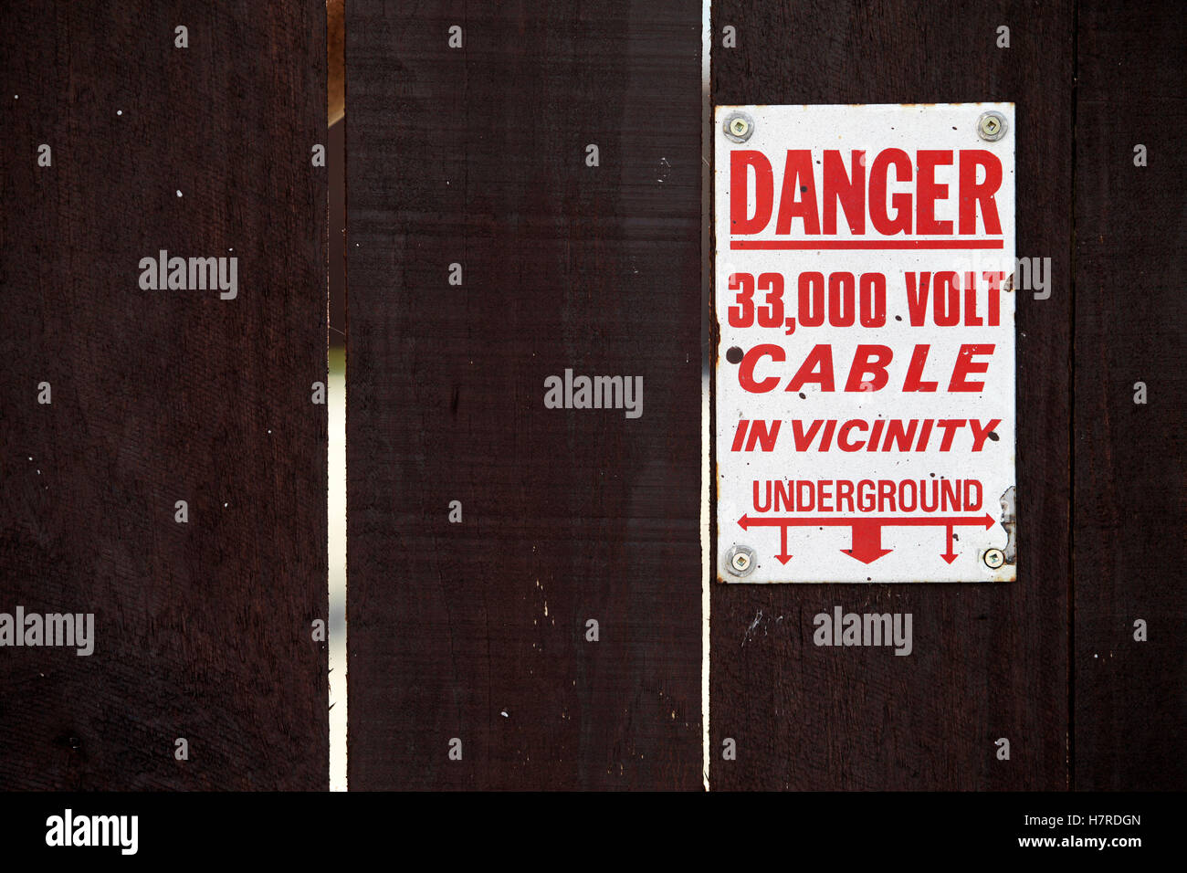 Señal de advertencia de alta tensión sobre la valla de madera en una subestación de Nueva Zelanda Foto de stock