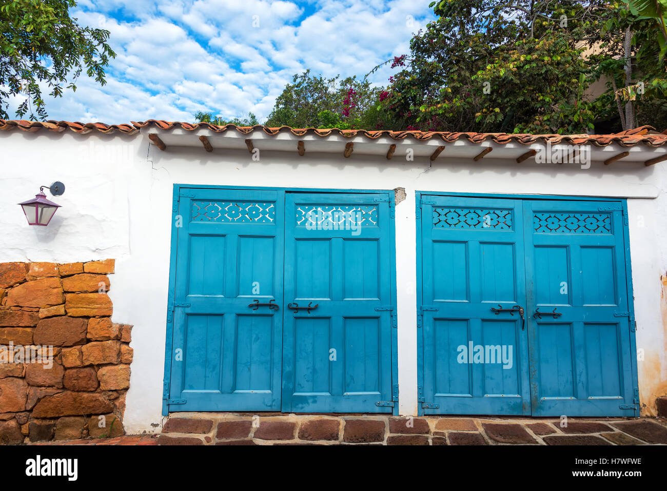 Puertas de garaje azul sobre fondo blanco edificio colonial en Barichara, Colombia Foto de stock