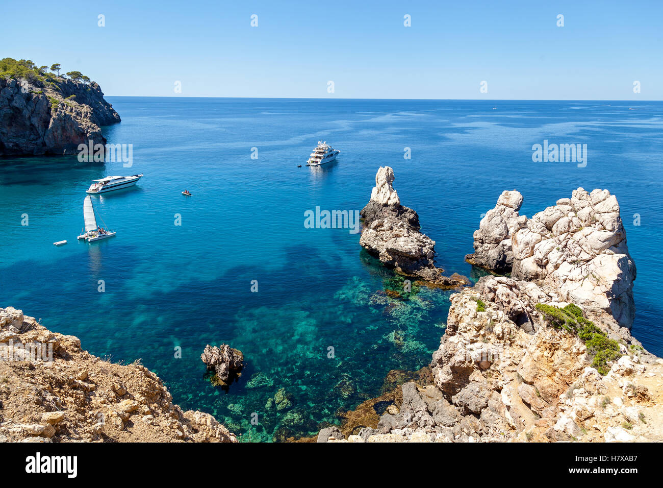Bahía Azul con aguas cristalinas, que ofrece increíbles vistas de las vastas extensiones. Velero con solitaria roca sobre las olas y vaya yo Foto de stock