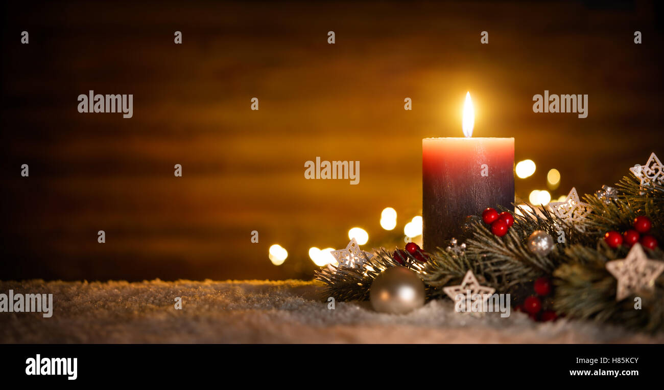 Velas encendidas y decoración de Navidad en nieve y fondo de madera, elegantes bajo llave shot con ánimo festivo Foto de stock